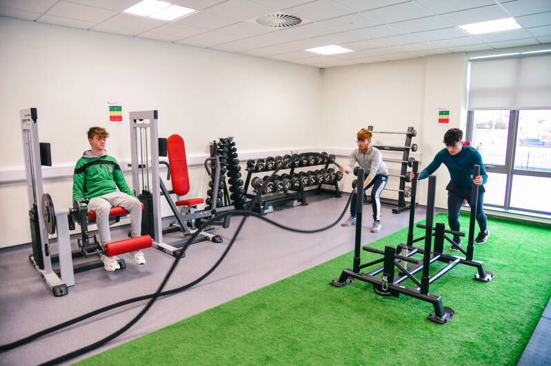 SRC students using campus fitness suite. Equipment includes a weights machine and battle ropes.