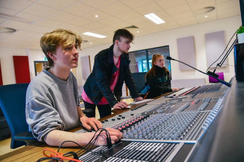 Two SRC students are using mixing desk in music studio